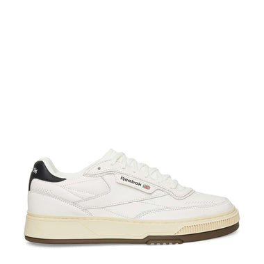 A white Reebok sneaker with a beige sole, black heel detail, and Reebok logo on the side, shown in a side profile on a plain white background.