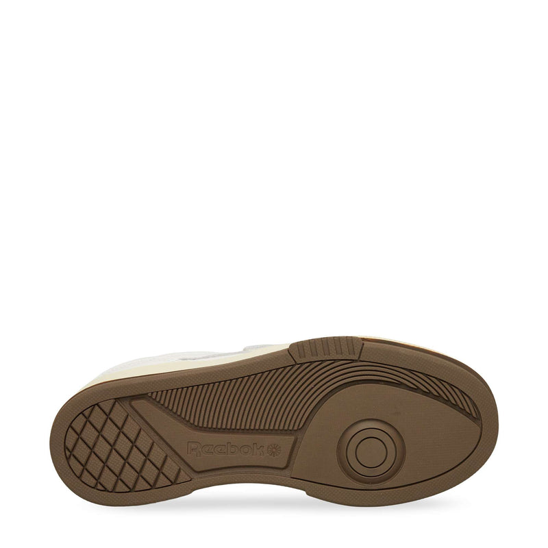 The image shows the brown rubber sole of a Reebok sneaker with a geometric tread pattern, grid detail at the heel, and Reebok branding embossed near the center.