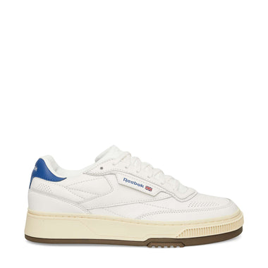 The Reebok Club C LTD Shoes are classic white tennis shoes with a blue heel detail, beige midsole, brown outsole, and feature the Reebok logo plus a small Union Jack flag on the side.