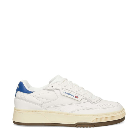 The Reebok Club C LTD Shoes are classic white tennis shoes with a blue heel detail, beige midsole, brown outsole, and feature the Reebok logo plus a small Union Jack flag on the side.