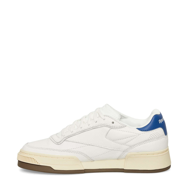 The Reebok Club C LTD Shoes feature white leather, a cream sole, brown outsole, blue heel accent, white laces, and minimalist Club C branding on the heel tab.