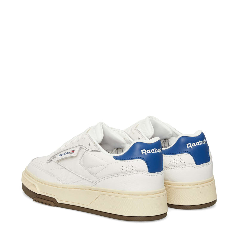 A pair of Reebok Club C LTD Shoes in white with beige soles and blue heel tabs, displayed from back and side angles on a plain white background.
