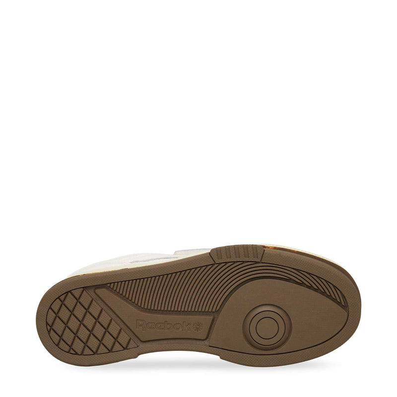 The image displays the brown rubber outsole of the Reebok Club C LTD Shoes with textured tread patterns, including circular and linear designs for traction, plus an embossed Reebok logo near the heel.
