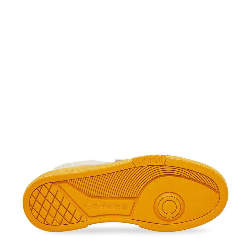 The image shows the yellow sole of Reebok Club C LTD Shoes from below, featuring textured patterns, circular and linear tread designs, and the Reebok logo—highlighting its classic tennis heritage.