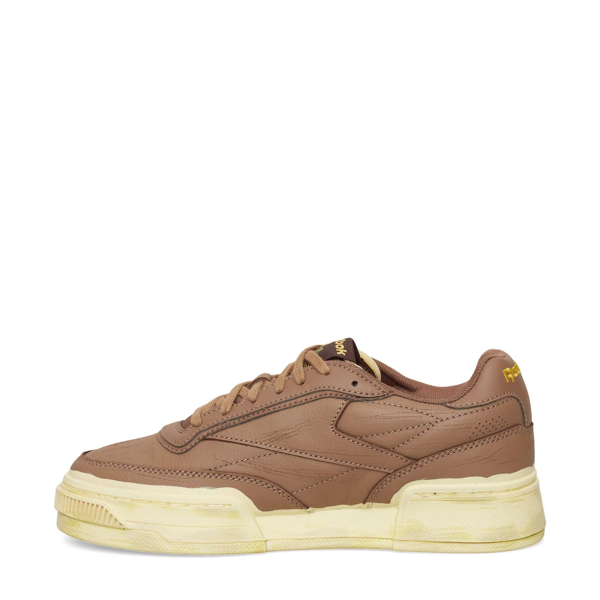 The Reebok Club C LTD Shoes feature brown leather, a thick off-white sole, subtle stitching, a low-top design, and yellow Reebok branding near the heel and tongue—perfect for a classic lifestyle look.