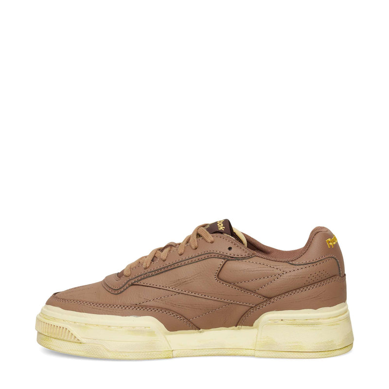 The Reebok Club C LTD Shoes feature brown leather, a thick off-white sole, subtle stitching, a low-top design, and yellow Reebok branding near the heel and tongue—perfect for a classic lifestyle look.