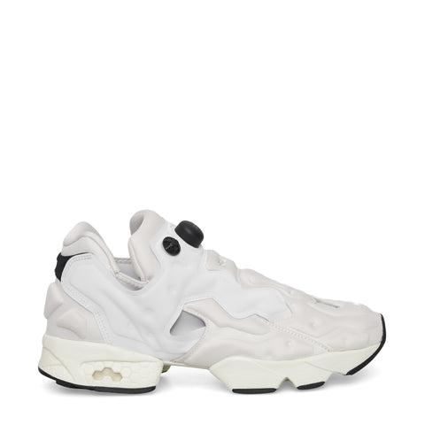 A white sneaker with a chunky, sculpted sole, black accents on the heel and sole, and unique cutouts and bubble-like details on the upper, shown in a side profile on a plain background.