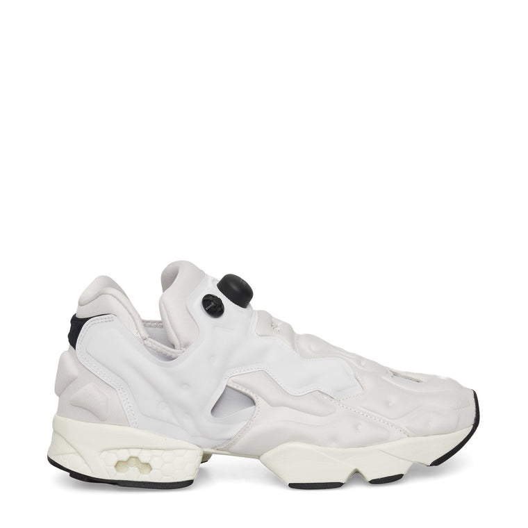 A white sneaker with a chunky, sculpted sole, black accents on the heel and sole, and unique cutouts and bubble-like details on the upper, shown in a side profile on a plain background.