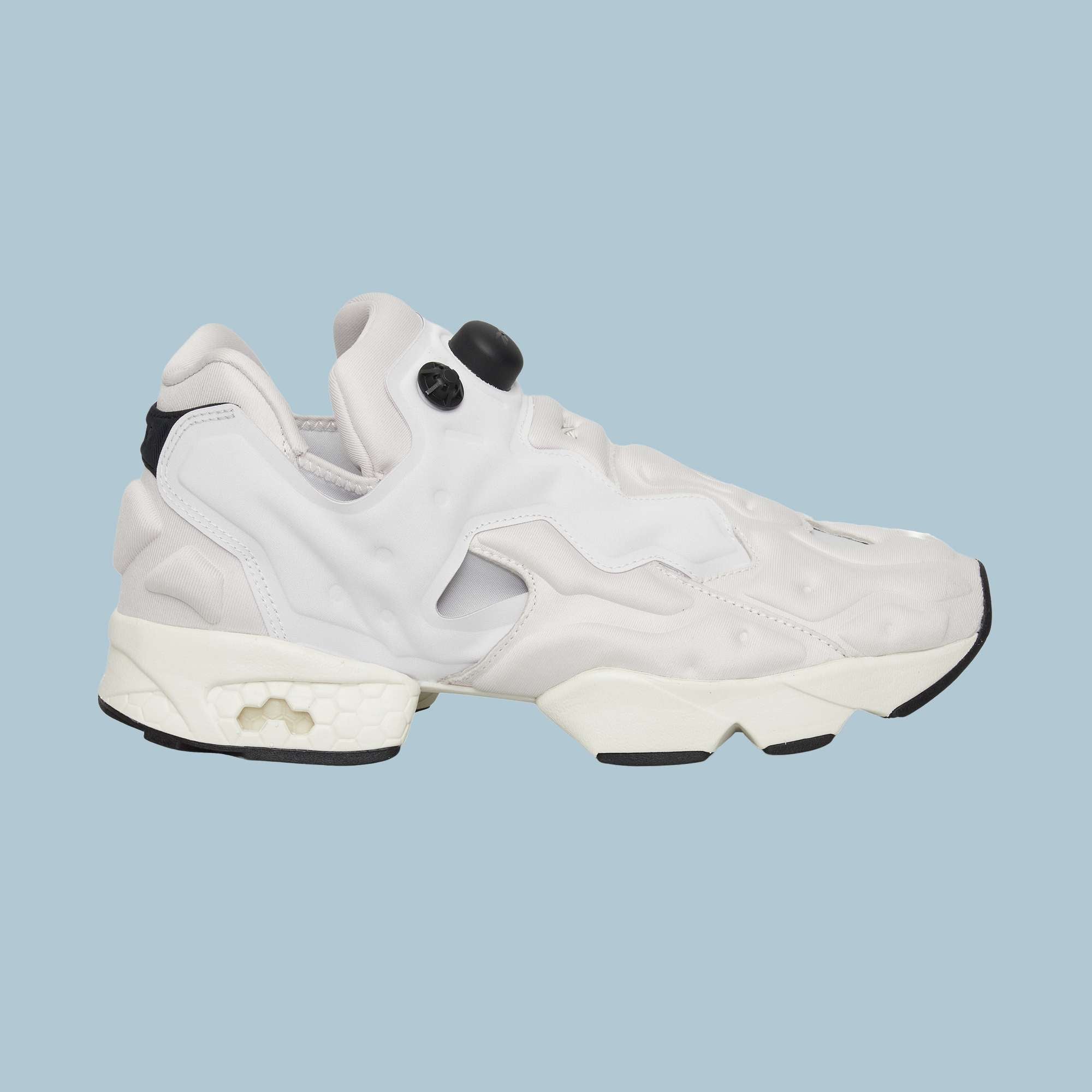 The Reebok Instapump Sliver Shoes are white and light gray sneakers with a chunky sole and unique cutout design, featuring Hexalite cushioning for comfort, displayed from the side on a light blue background.