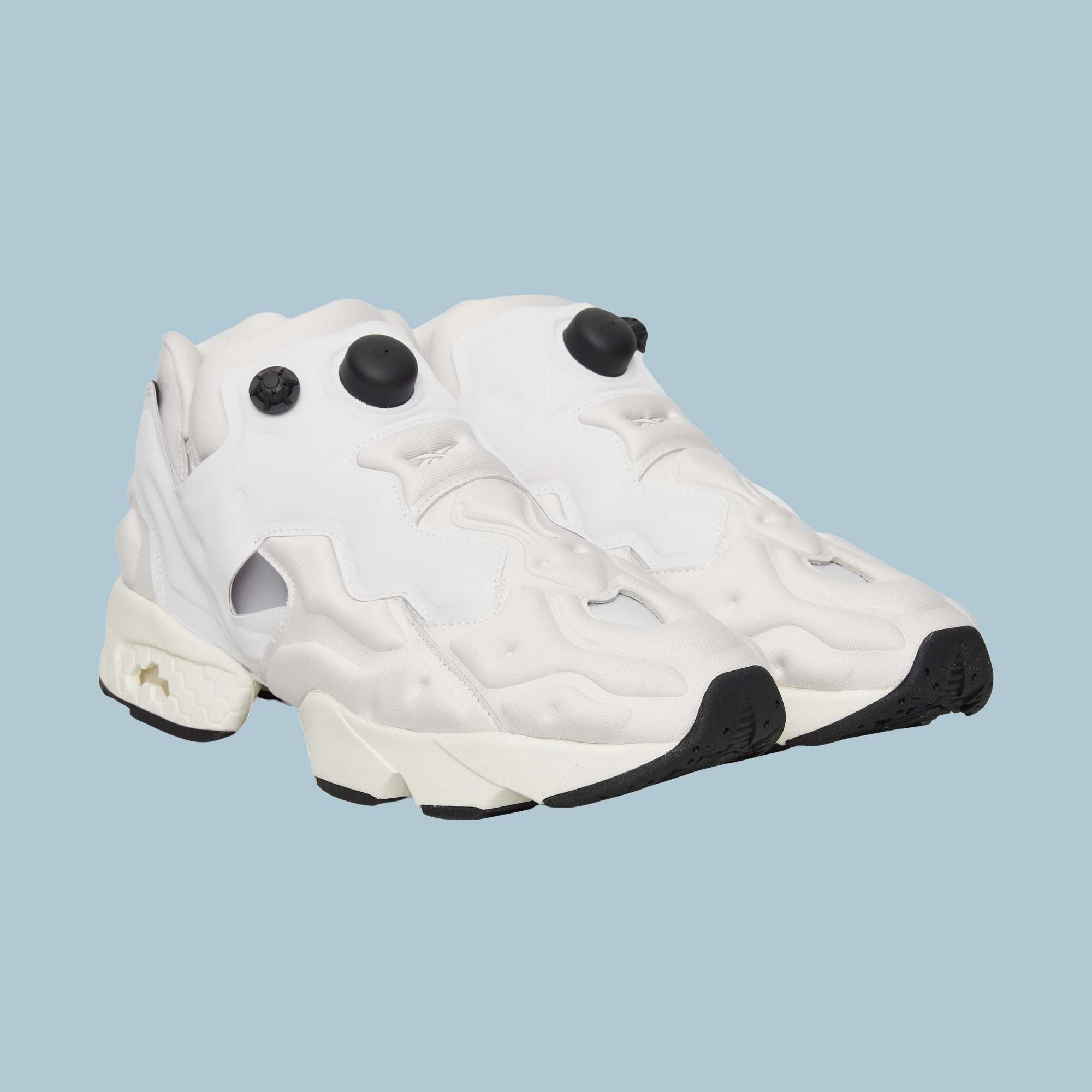 A pair of Reebok Instapump Sliver Shoes in white, featuring chunky soles, black outsoles, and distinctive black pump buttons with InstaPump technology—displayed against a plain light blue background.