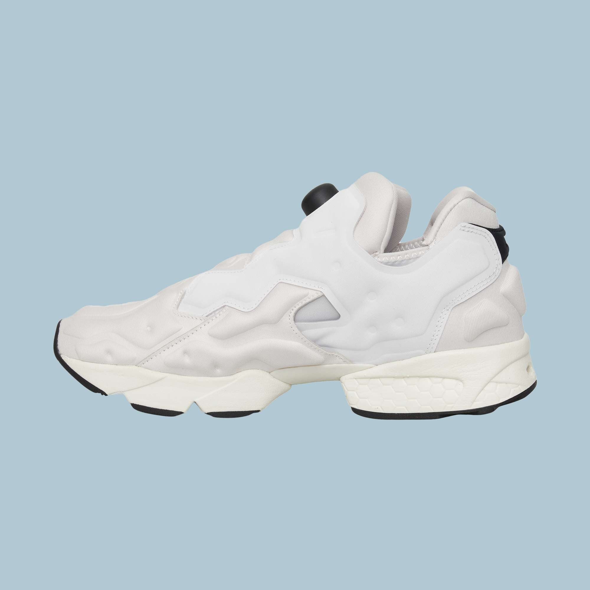The Reebok Instapump Sliver Shoes feature a modern white and light gray design with black accents, a chunky sole, futuristic style, and Hexalite cushioning. Displayed on a light blue background.
