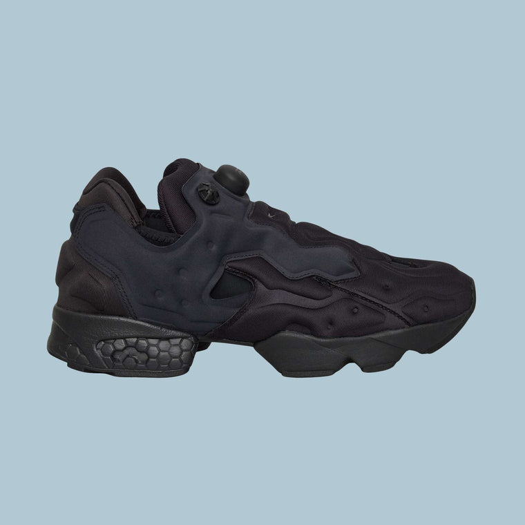 The Reebok Instapump Sliver Shoes are black athletic sneakers with a futuristic design, chunky sole, heel Hexalite cushioning, and a pump button on the tongue, shown against a light blue background.