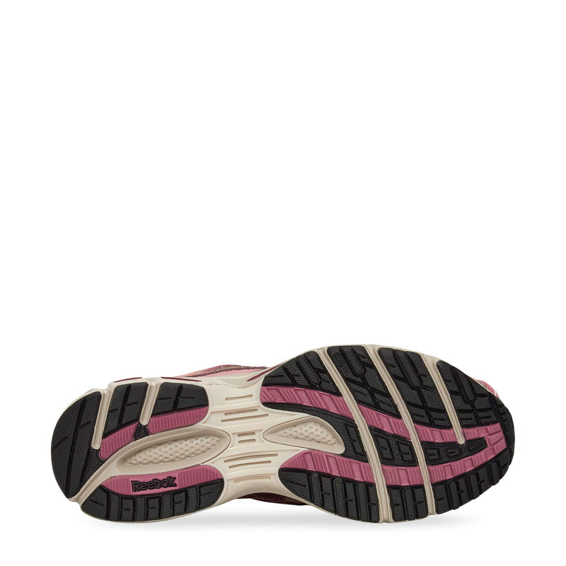 The image displays the outsole of the Reebok Premier Road Ultra Shoes, showcasing a treaded black sole with beige and pink accents, the Reebok logo by the heel, traction grooves, and cushioning from a dual-density midsole.