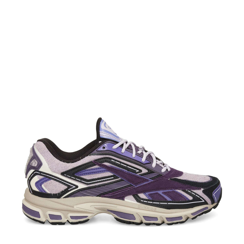 The Reebok Premier Road Ultra Shoes are stylish athletic sneakers inspired by archival runners, featuring layered suede and mesh panels in purple, black, and beige with a chunky sole, dual-density midsole, and white laces.
