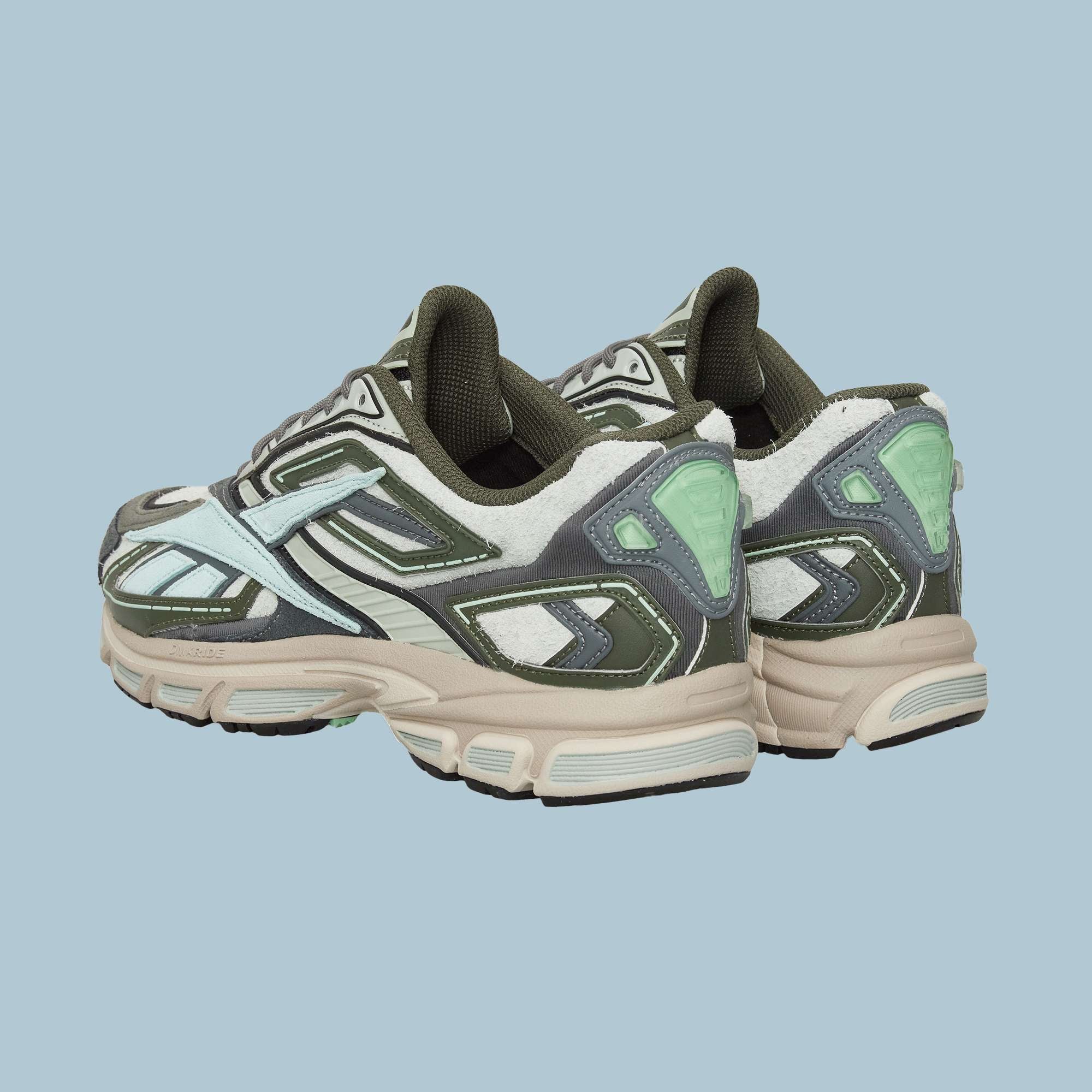 A pair of Reebok Premier Road Ultra Shoes in green, white, and mint with chunky beige soles and a dual-density midsole is displayed on a light blue background, shown from the back and side.