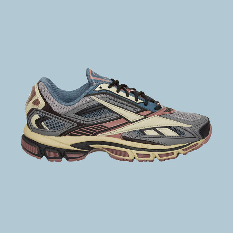 The Reebok Premier Road Ultra Shoes are shown in a left side profile on a light blue background, featuring a multicolored design with gray, blue, burgundy, cream, and black accents and a dual-density midsole for enhanced comfort.