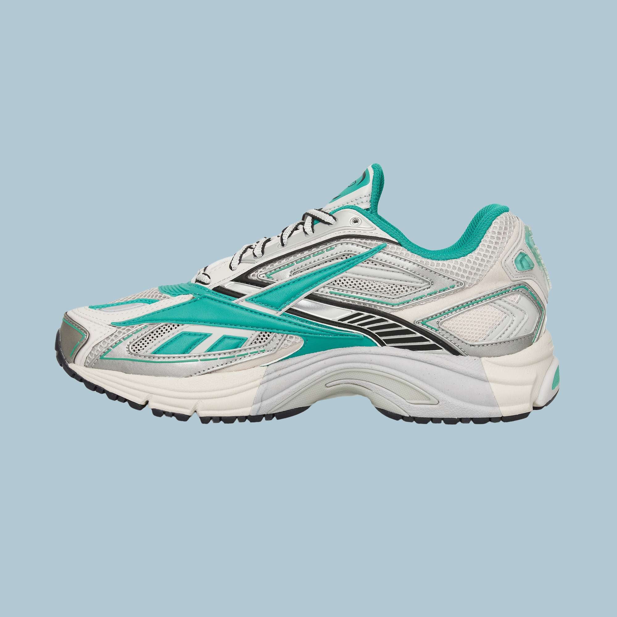 The Reebok Premier Road Ultra Shoes are white athletic sneakers with teal and black accents, shown from the side on a light blue background. Inspired by archival running styles, they feature mesh panels and a dual-density midsole for comfort.