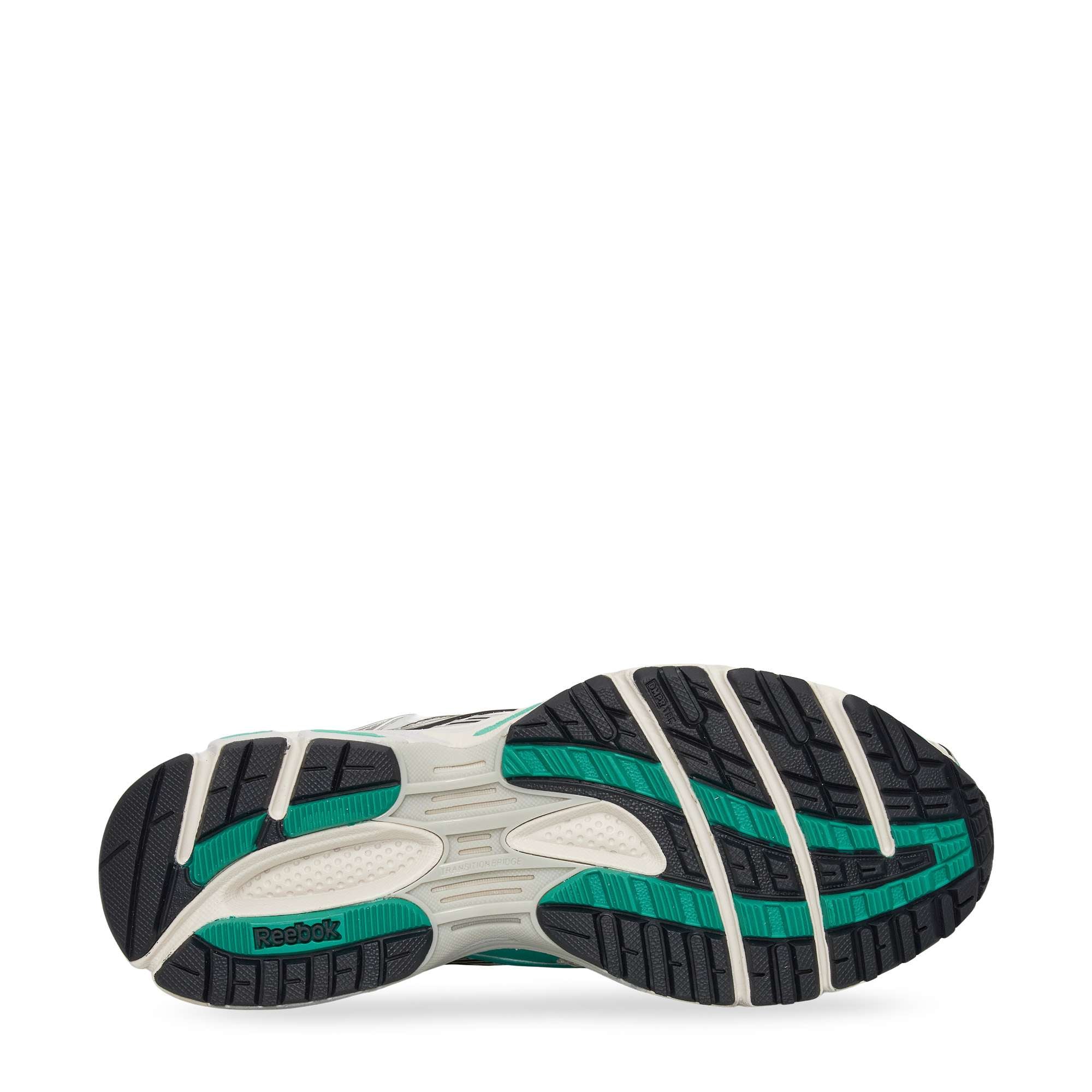 The image shows the sole of a Reebok sneaker, featuring a black and green tread pattern with white accents. The Reebok logo is visible in green near the heel area.