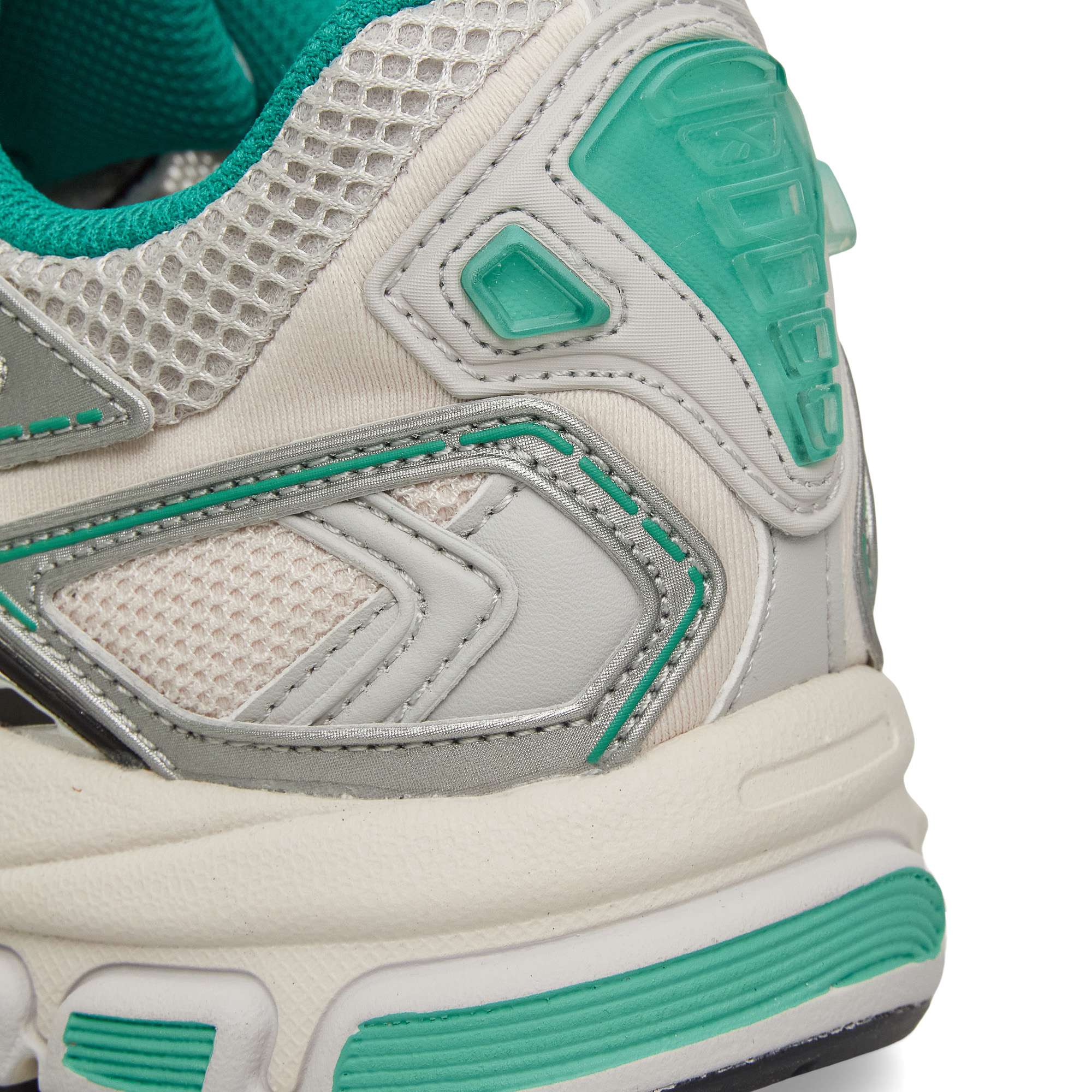 Close-up of the heel and side of a sports sneaker, featuring white, gray, and teal colors with textured mesh, leather, and rubber details. The design includes stitching and geometric patterns.
