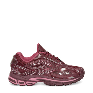 The Reebok Premier Road Ultra Shoes feature a maroon mesh upper with pink accents, silver detailing, and laces. A thick textured sole offers comfort and stability, making them ideal for running or casual wear.