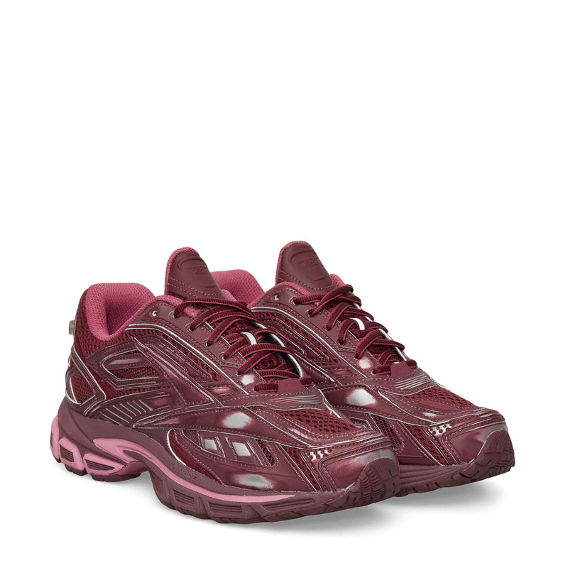 A pair of maroon Reebok Premier Road Ultra Shoes with a glossy finish and pink accents, thick soles, and textured details for comfort and stability, shown side by side on a white background.