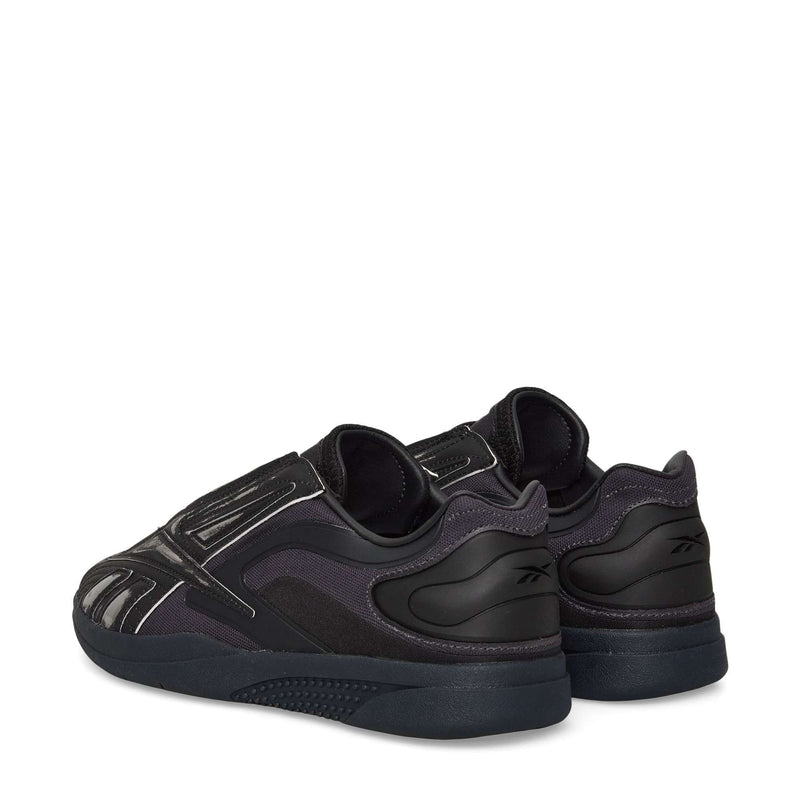 A pair of Reebok Hammer Pro LTD Shoes in black, featuring a faux leather upper, textured rubber sole, and reflective silver accents, shown from back and side angles on a white background.