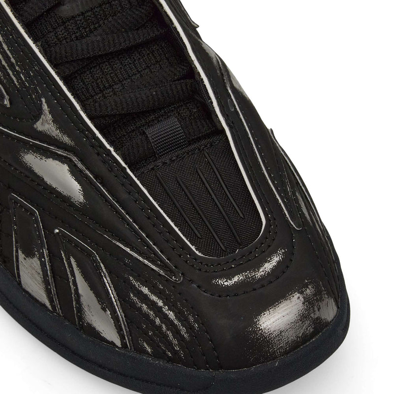 Close-up of the front and side of Reebok Hammer Pro LTD Shoes in black, featuring a shiny, textured faux leather upper with black laces and detailed stitched and grooved designs on the material.
