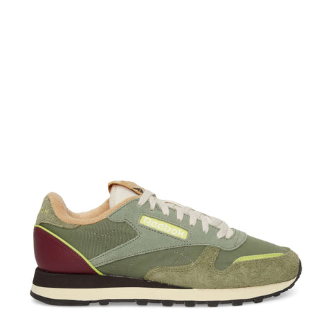 The Reebok Classic Leather Premium LTD Shoes in green feature suede and leather panels, beige laces, a maroon heel accent, and a cream and black sole. A classic silhouette highlights the yellow Reebok logo on the side.