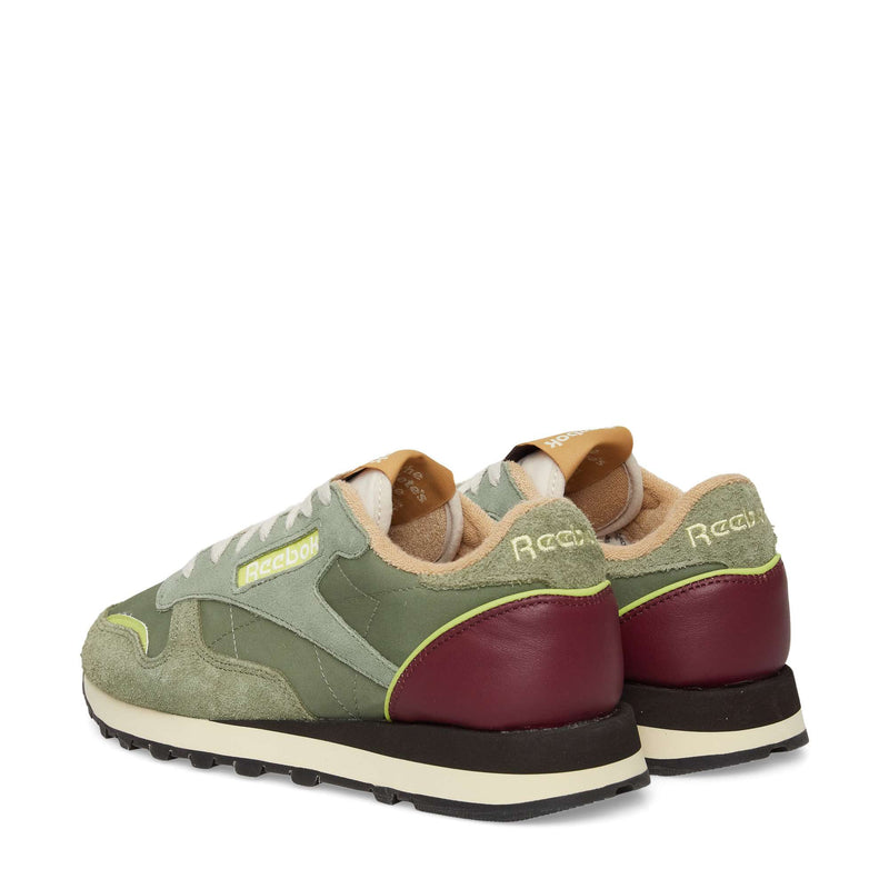 The Reebok Classic Leather Premium LTD Shoes are retro sneakers with green suede and mesh uppers, maroon heel accents, yellow branding, a classic silhouette, white laces, and beige interior lining—shown from the back and side.