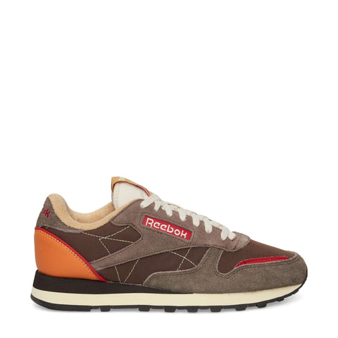 The Reebok Classic Leather Premium LTD Shoes feature a brown and taupe colorway with red and orange accents, white stitching, classic silhouette, white laces, black and white sole, and visible Reebok logos for a retro sneaker vibe.