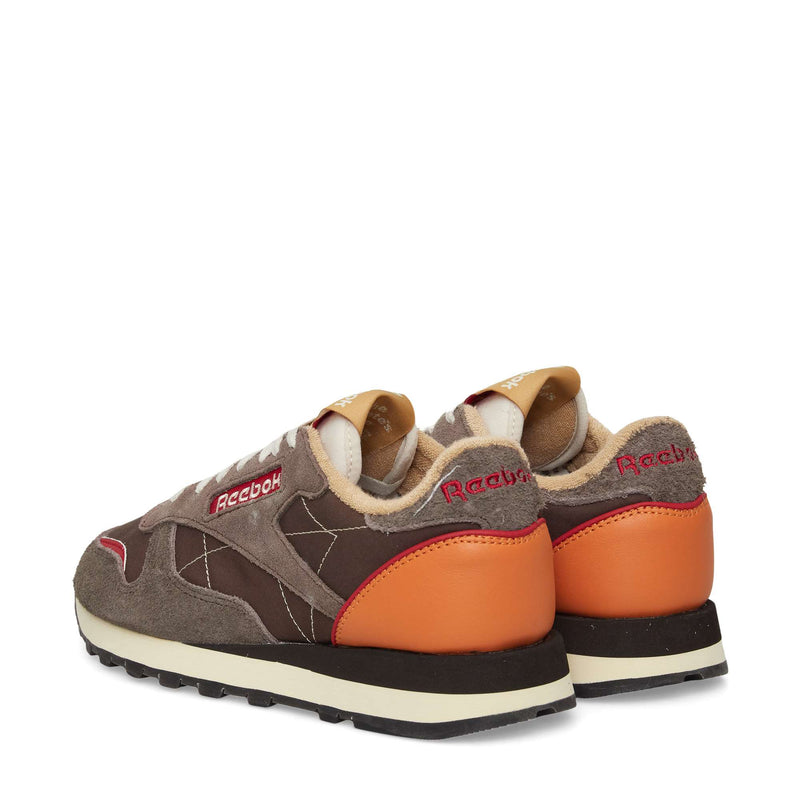 A pair of Reebok Classic Leather Premium LTD Shoes shown from the back and side, with brown suede and leather panels, orange heel accents, beige lining, and red Reebok branding—retro sneakers with a classic silhouette.
