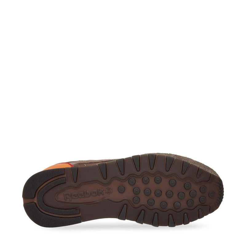The image displays the bottom of a brown Reebok Classic Leather Premium LTD Shoe, highlighting its textured rubber sole with circular grips and the embossed Reebok logo near the heel—reflecting its signature classic design.