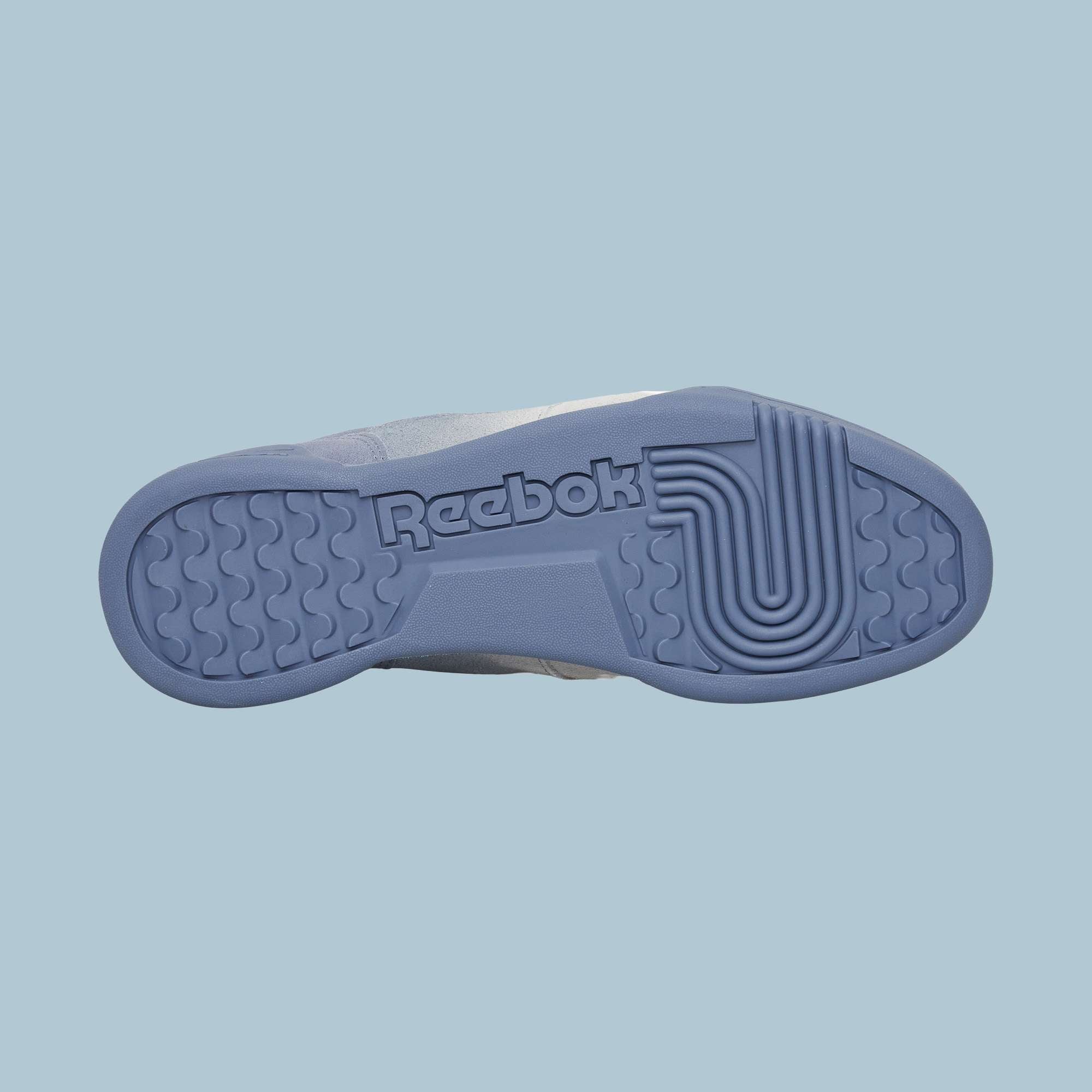 Against a light blue background, the textured sole of the Reebok Workout Plus Og Shoes is displayed, featuring the Reebok logo and reflecting the classic retro silhouette of these sneakers.