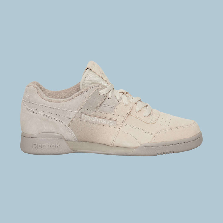 The Reebok Workout Plus Og Shoes feature a beige suede upper, tonal laces, and an off-white sole, highlighting their classic silhouette against a light blue background.