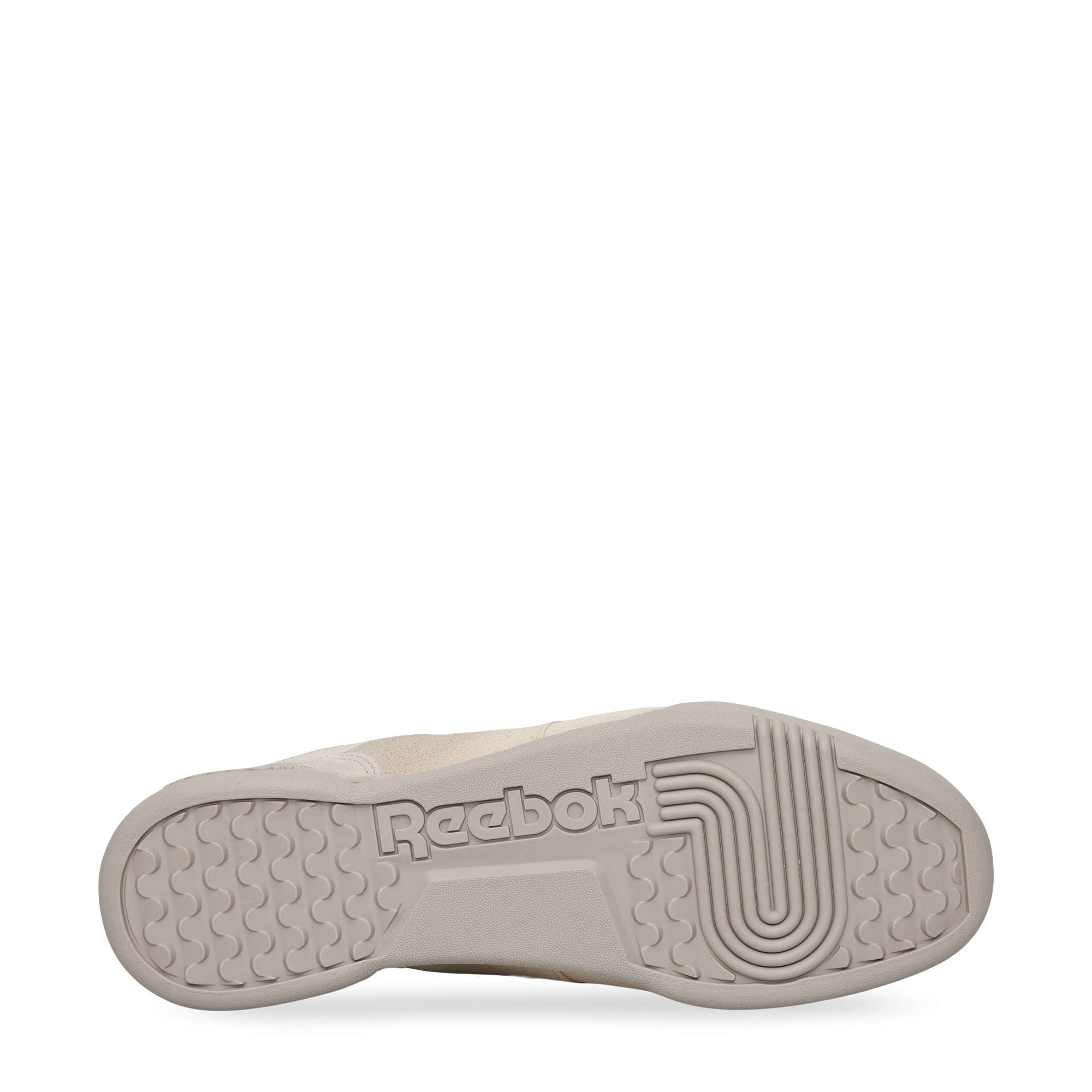A beige Reebok sneaker is shown from the bottom, displaying the sole with the Reebok logo and textured grip patterns. The background is white.