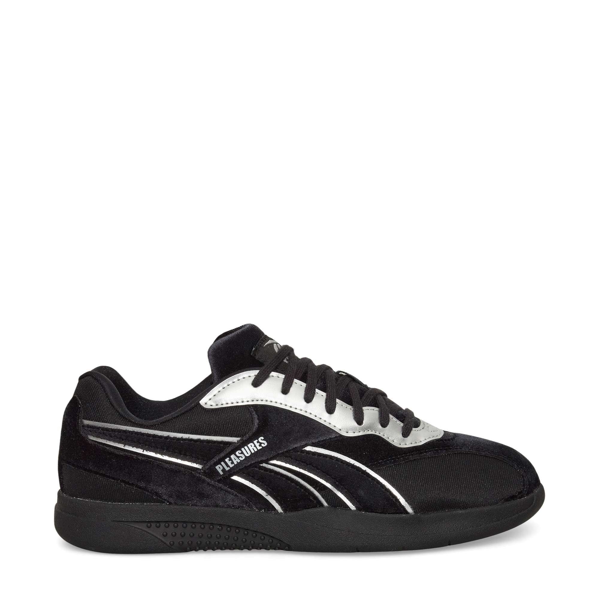 A black low-top sneaker with black laces, silver accents, and the word PLEASURES printed on the side. The shoe has a black sole and a sleek, modern design.