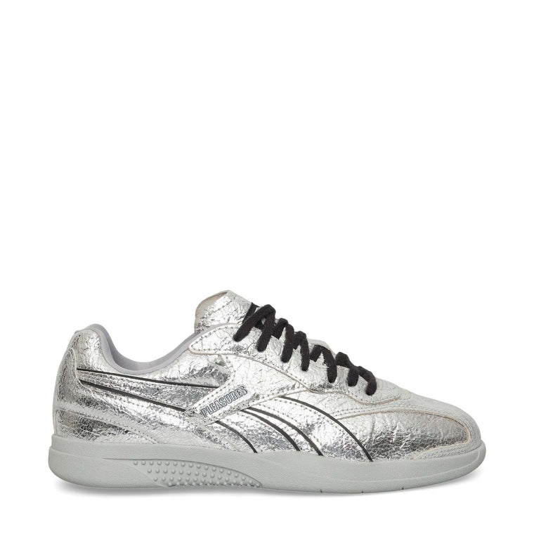 A metallic silver low-top sneaker with black laces, a light gray sole, and black detailing, viewed from the side against a white background.