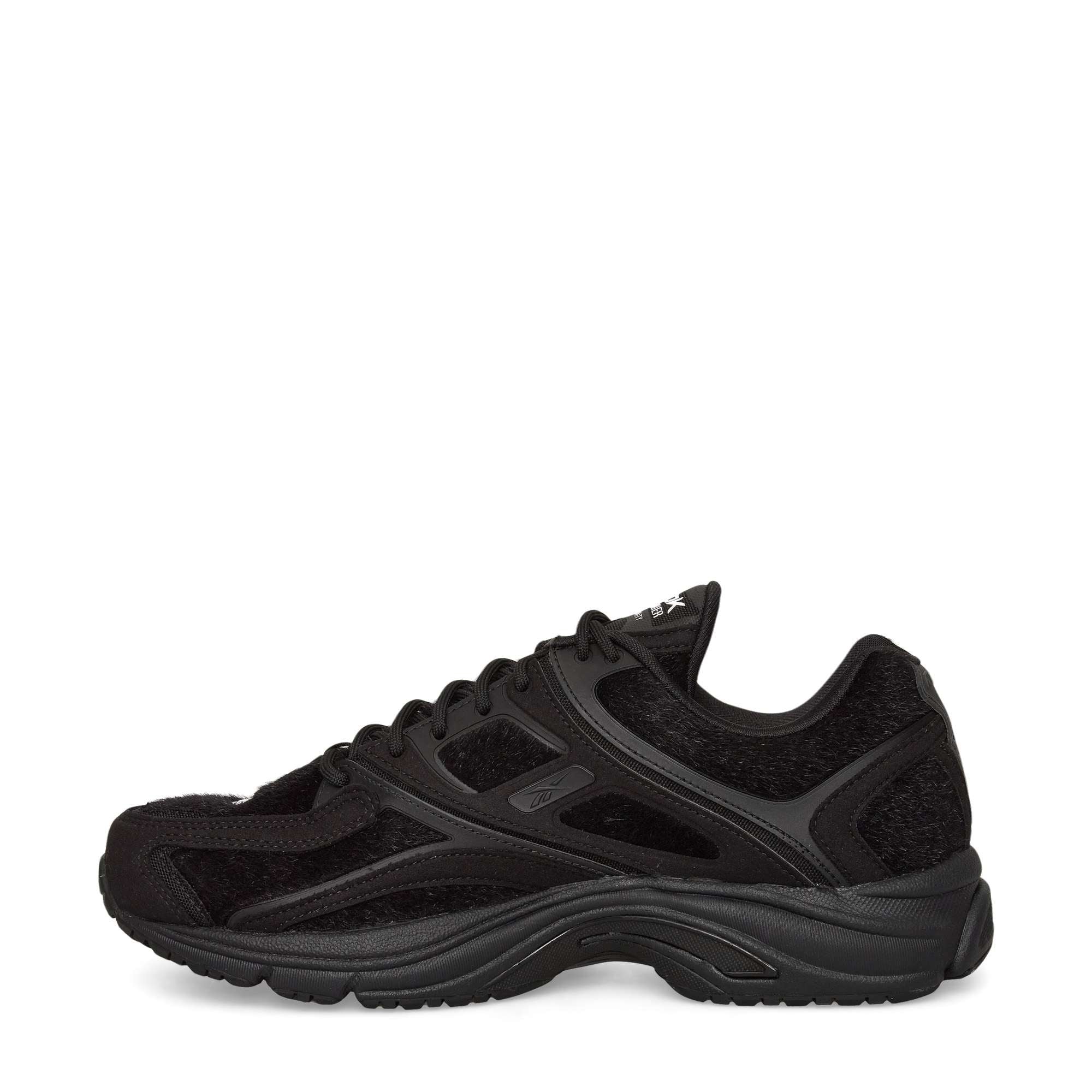 A black athletic sneaker with mesh and suede-like overlays, lace-up closure, and a textured rubber sole, shown in a side profile view on a white background.