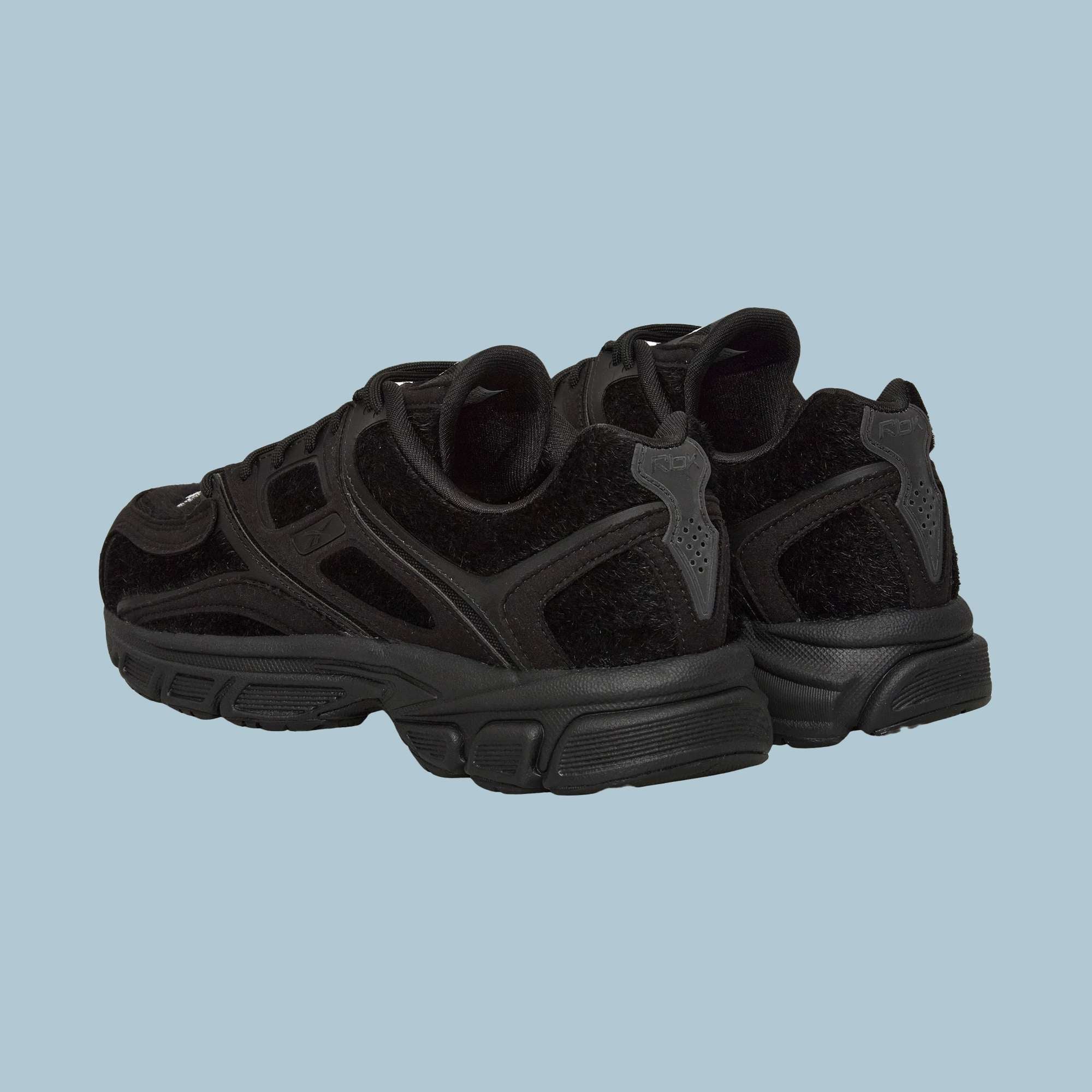 A pair of Reebok Pleasures Premier Trinity KFS Shoes with textured suede, mesh, and pony hair uppers, shown from the back and side against a plain light blue background.