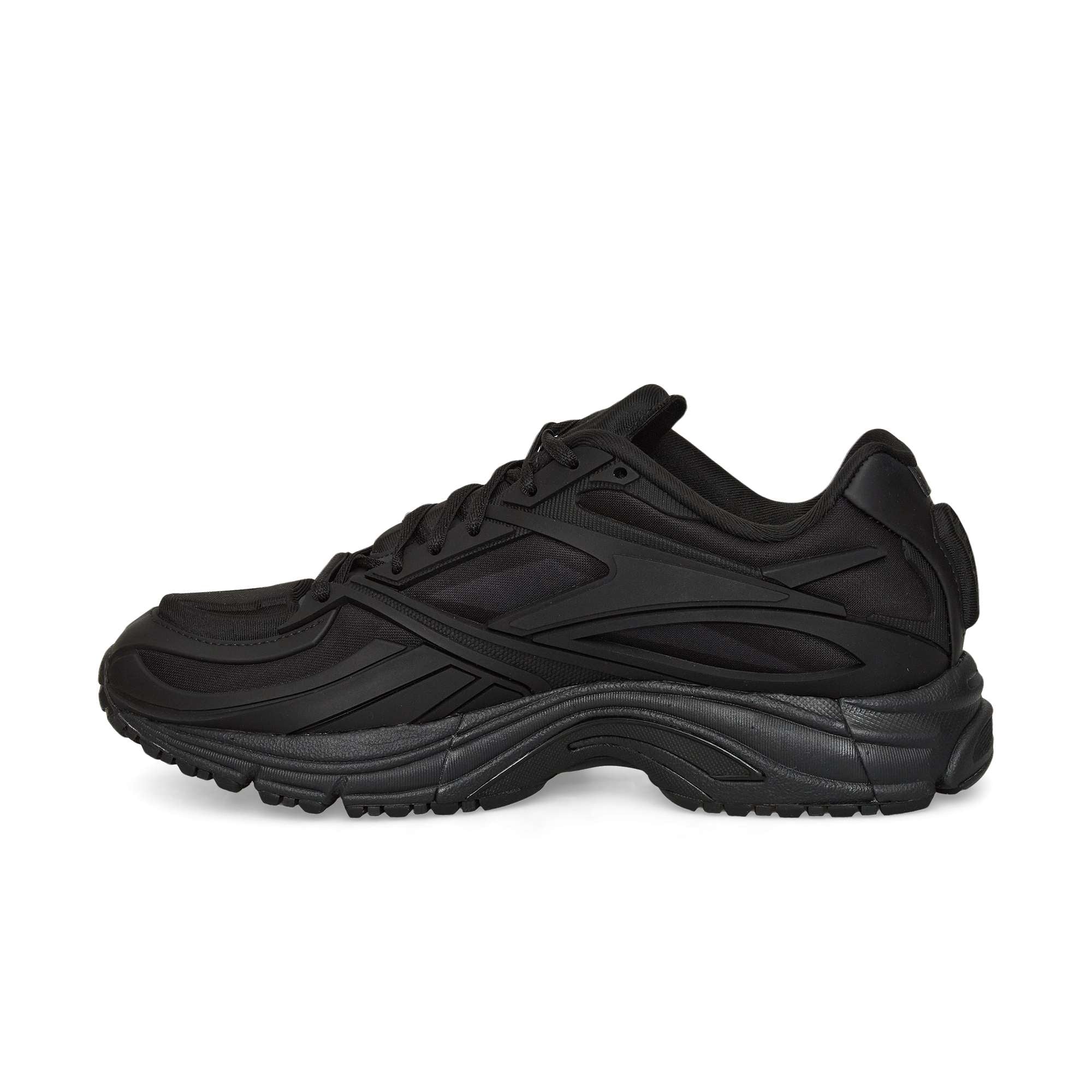 The Reebok Premier Road Modern running shoe in black features a textured sole, mesh and synthetic upper, and curved design lines, shown in side profile against a white background.