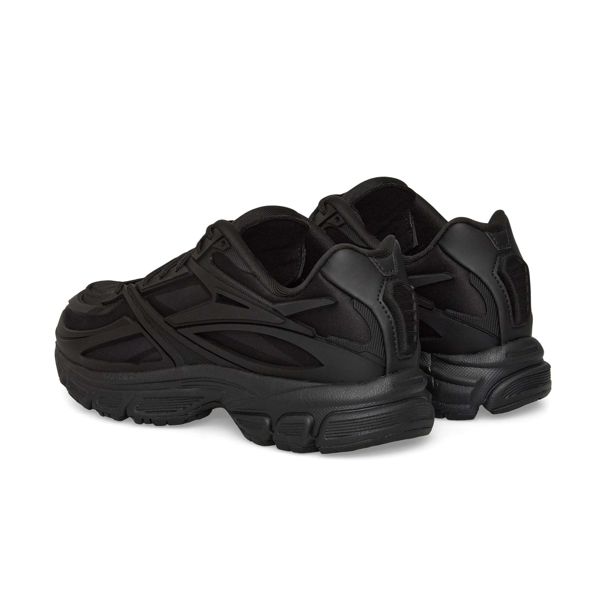 A pair of Reebok Premier Road Modern sneakers are shown from the heel, highlighting their chunky soles, dual-density midsole, and sleek design inspired by archival running shoe elements.