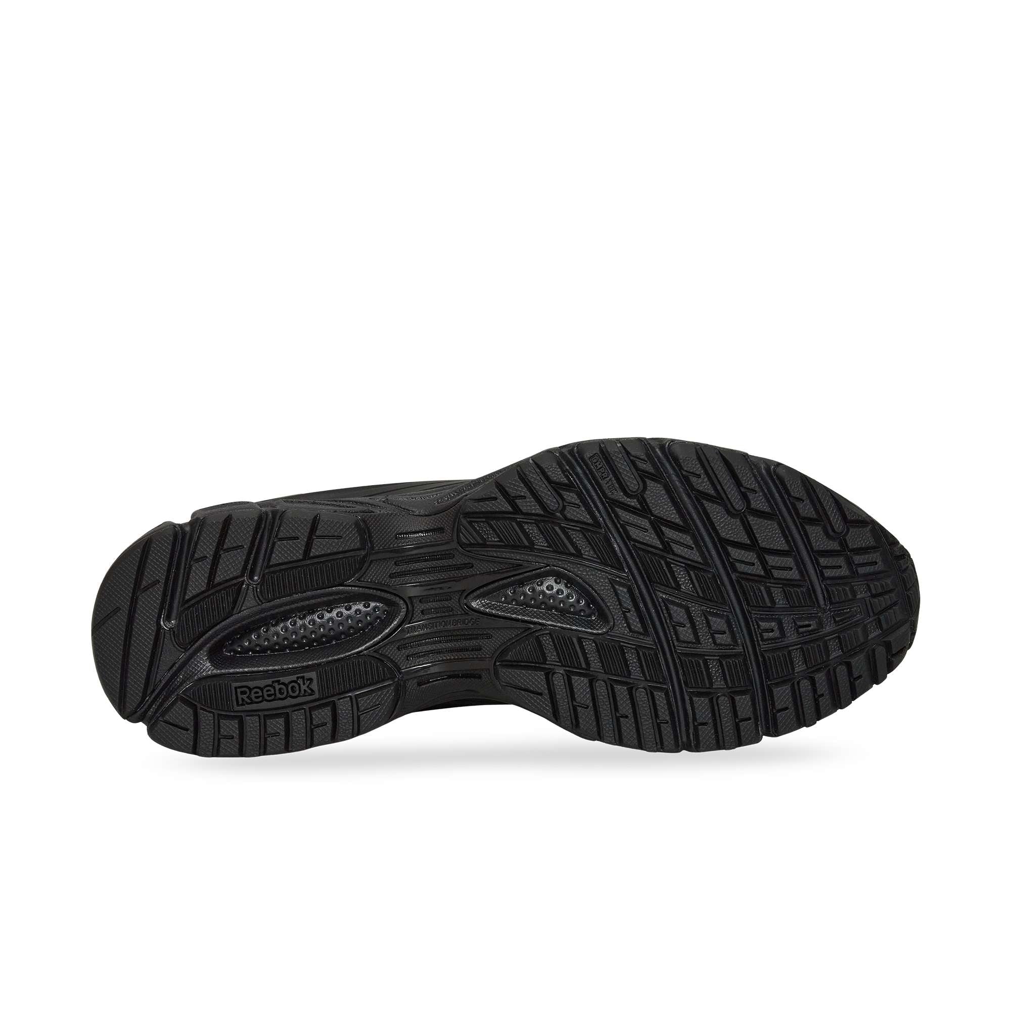 The image displays the black rubber sole of the Reebok Premier Road Modern, with textured patterns, grooves for traction, a dual-density midsole for comfort, and the Reebok logo by the arch.