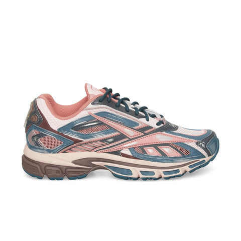 The Reebok Premier Road Ultra sneaker features a pink, blue, and cream color scheme, mesh panels, blue laces, and a thick multicolored sole. Inspired by archival running styles, it’s perfect for sporty or casual wear.