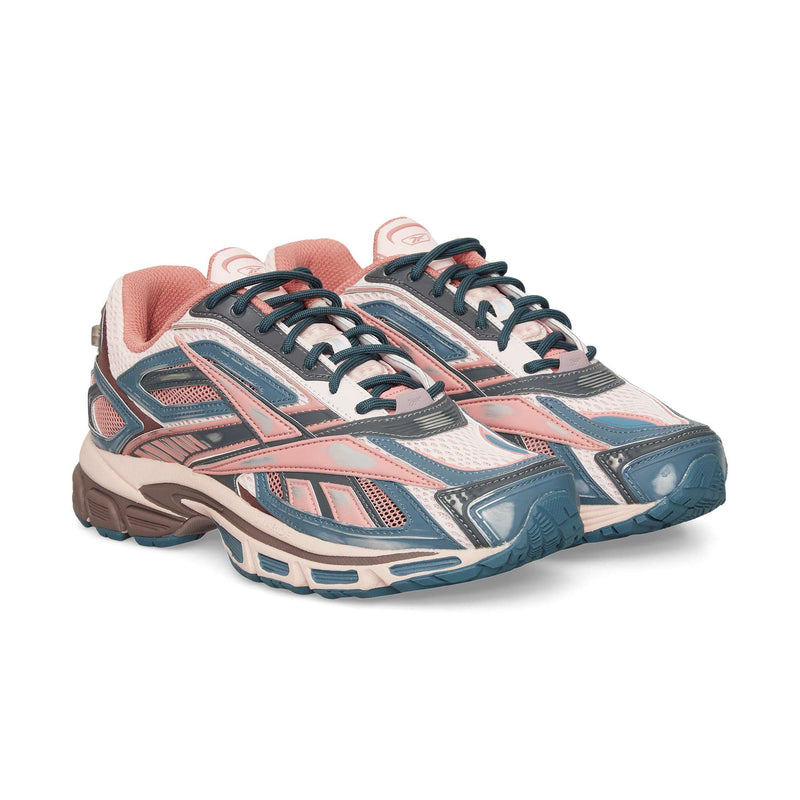 A pair of Reebok Premier Road Ultra sneakers, with pink, navy blue, white, and beige hues, chunky soles, mesh panels, and a dual-density midsole are placed side by side on a white background.