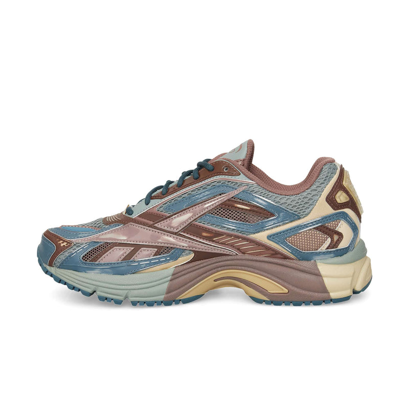A side view of the Reebok Premier Road Ultra sneaker shows blue, brown, beige, and tan accents with a mesh and synthetic upper, detailed panels, dual-density midsole, and a textured rubber sole.