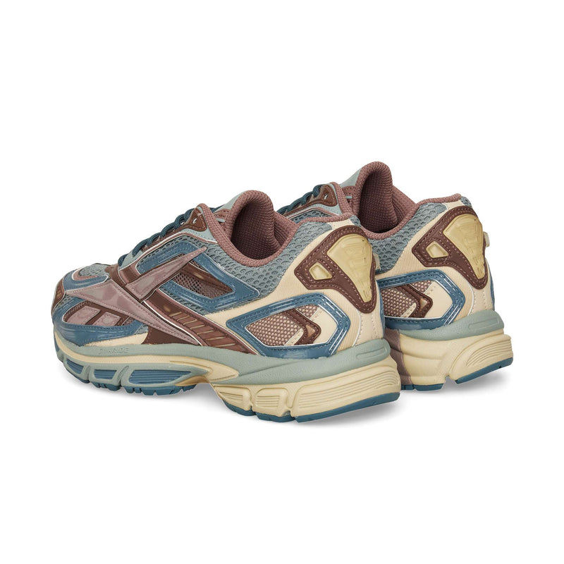 The Reebok Premier Road Ultra sneakers in blue, brown, beige, and gray are shown from the back and side on a white background. They feature a mesh upper, textured accents, thick soles, and a dual-density midsole.
