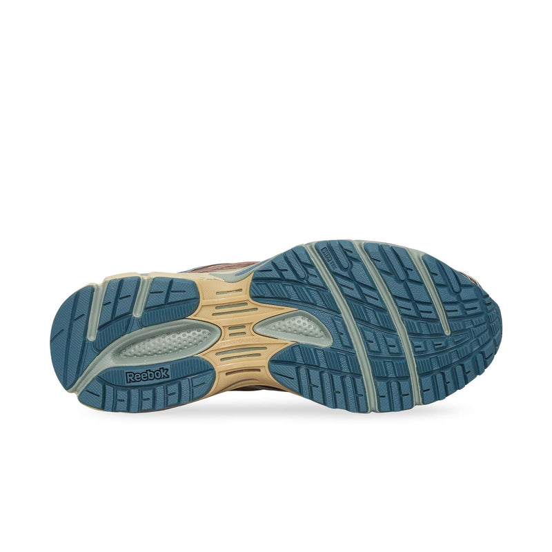The image shows the blue and beige rubber outsole of the Reebok Premier Road Ultra, featuring textured treads and grooves for grip, with the Reebok logo on the left side.