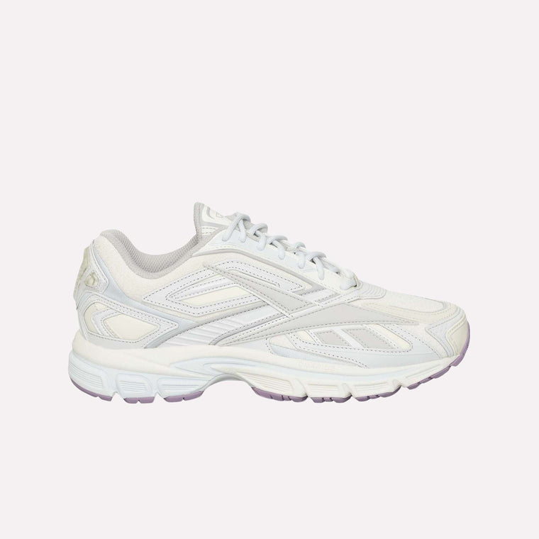 A white athletic sneaker with light gray accents, a textured sole, and lace-up closure is displayed on a plain white background. The Reebok Premier Road Ultra LTD Shoes are inspired by archival running sneaker design and feature a supportive dual-density midsole for enhanced comfort and performance.