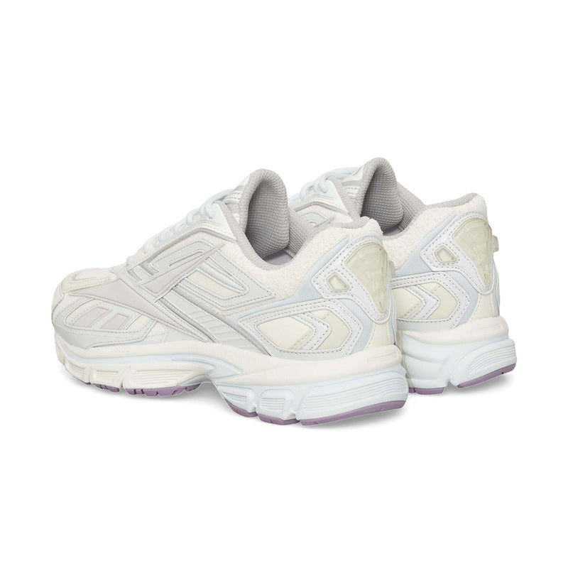 A pair of white Reebok Premier Road Ultra sneakers with light gray and off-white accents, viewed from the rear angle. Features include textured panels, a dual-density midsole, thick soles, and pale purple detailing on the outsole.