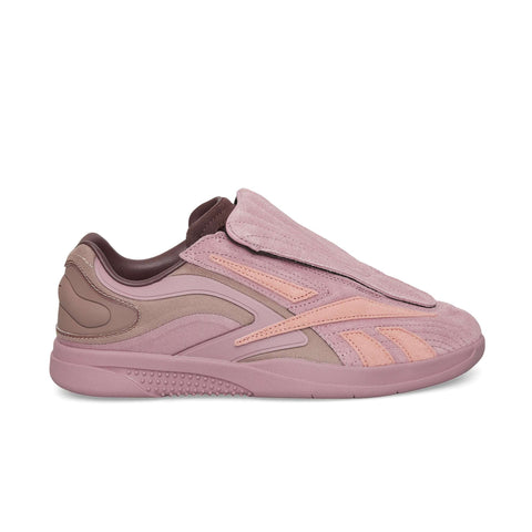 The Reebok Hammer Pro Ltd features a mauve and pink suede upper, a textured layered design, a large padded flap covering the laces, and a thick rubber sole with a bold pattern.